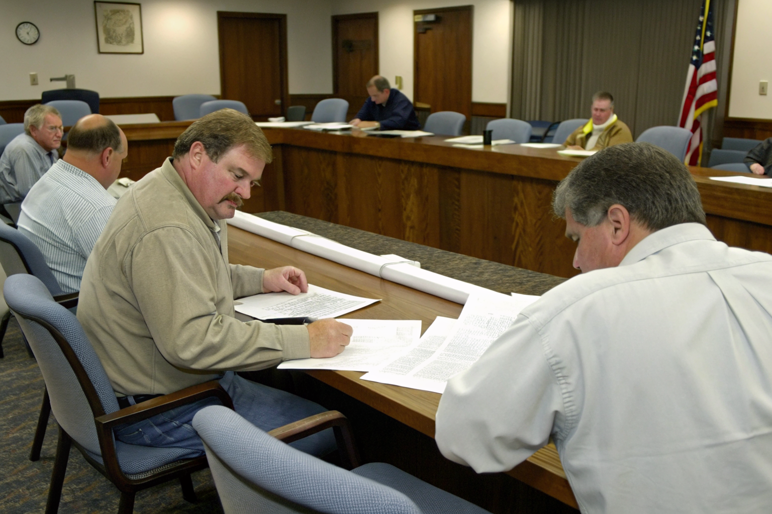 Officials reviewing sewage management plans in a meeting room.