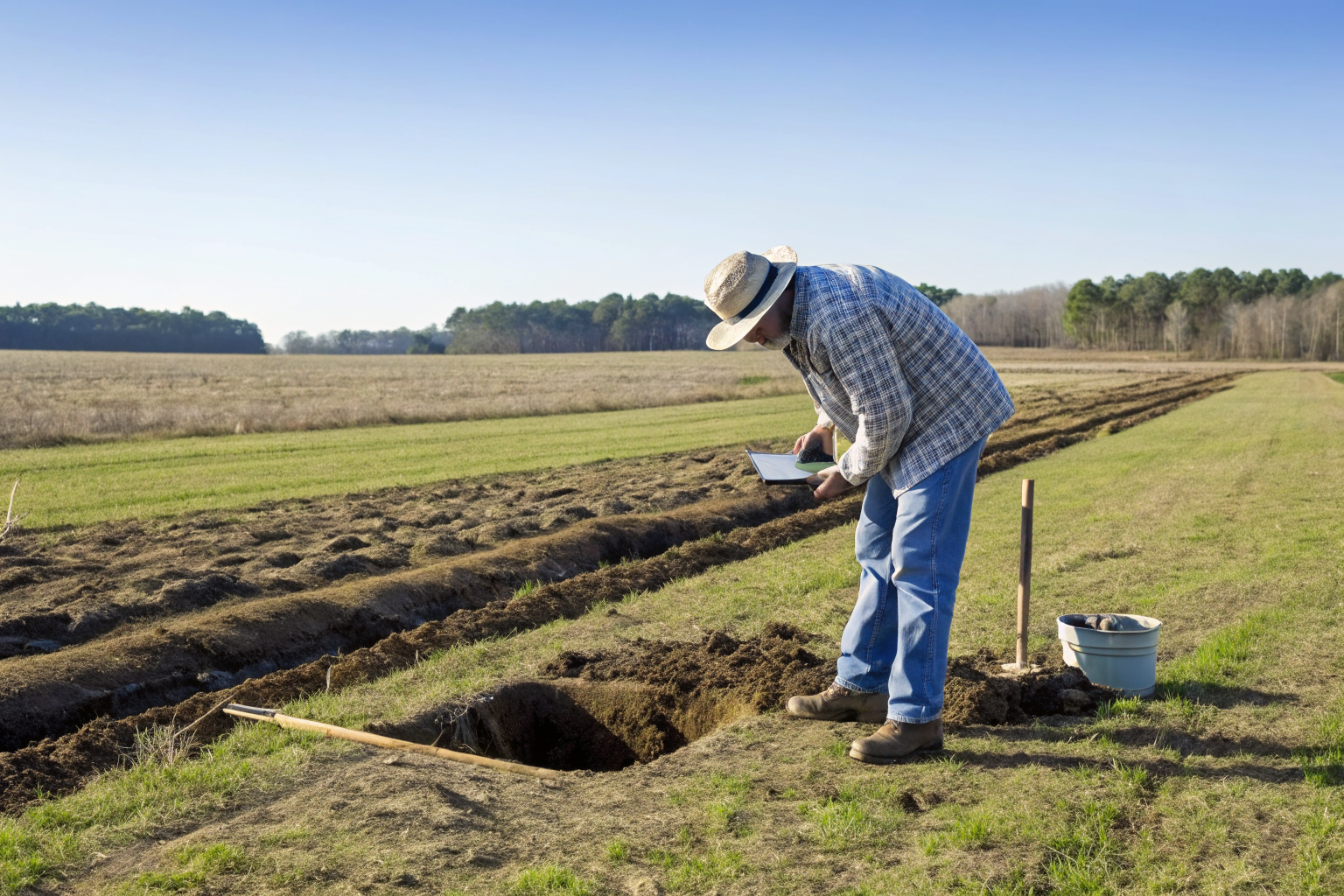 Soil scientist evaluates site by digging test hole in a North Carolina field.